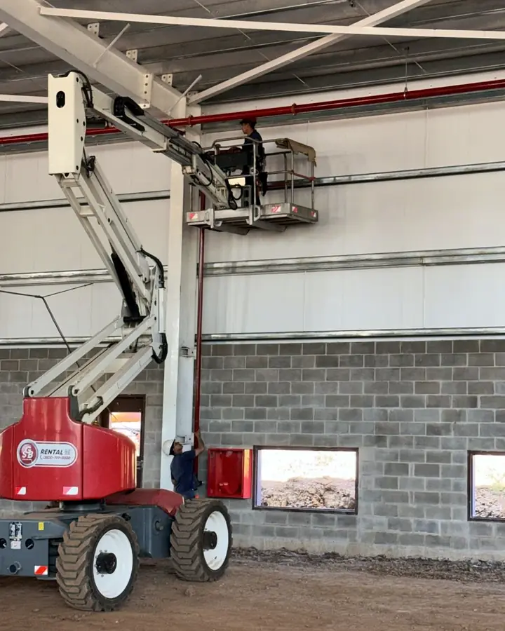 Plataforma articulada trabajando en altura dentro de una nave industrial